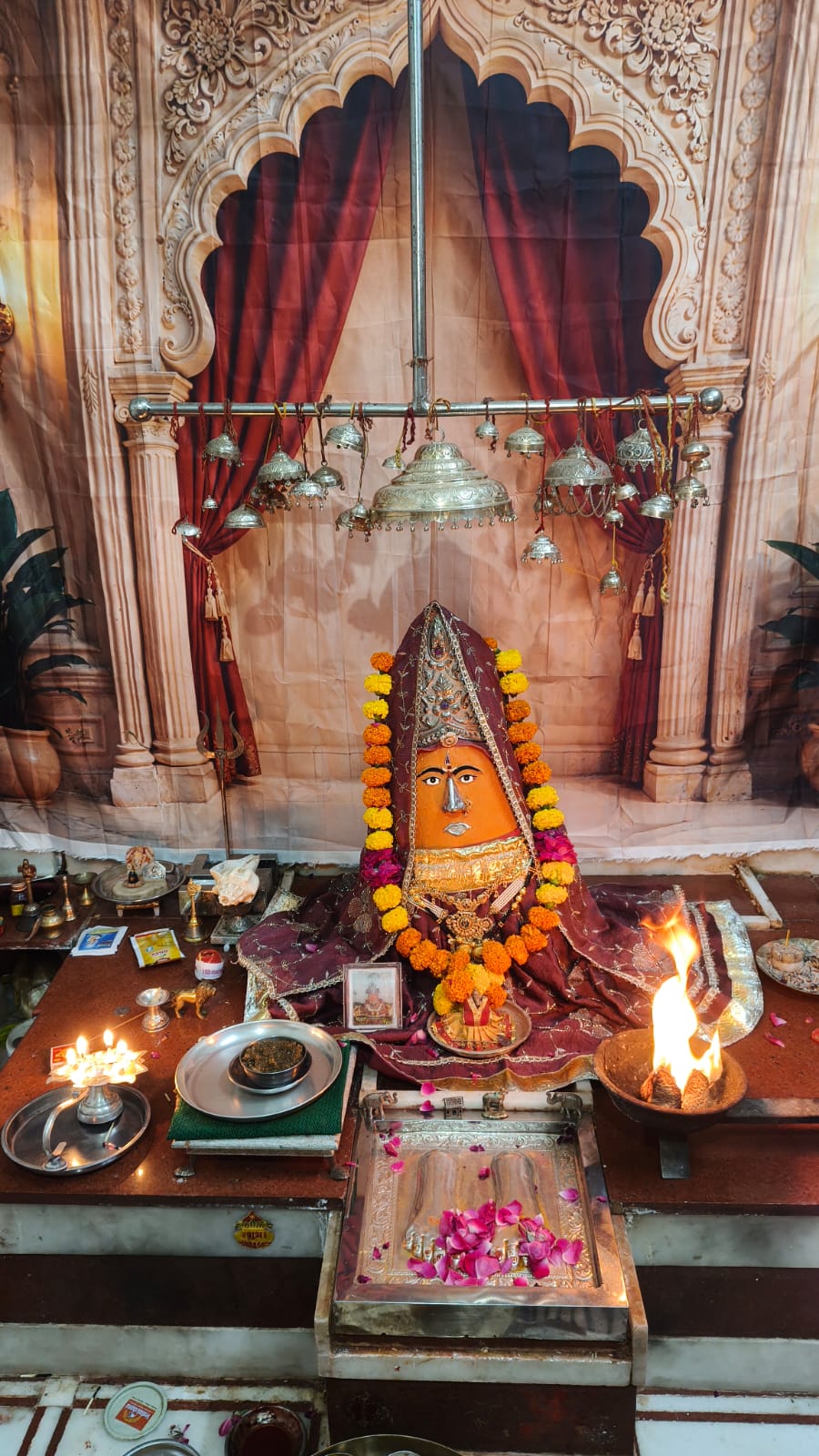 Sushmad Mataji at the shrine with lamps and floral offerings
